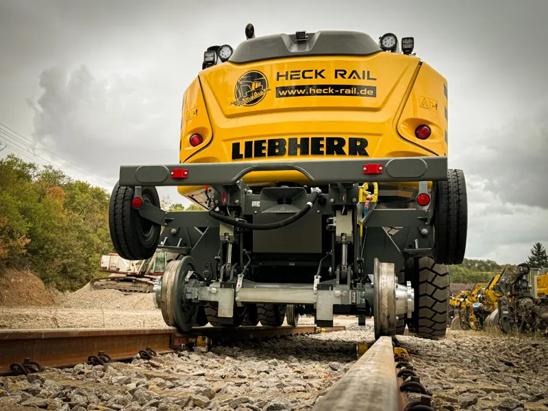 Heck des Zweiwegebaggers mit HECK RAIL-Logo auf dem Gleis